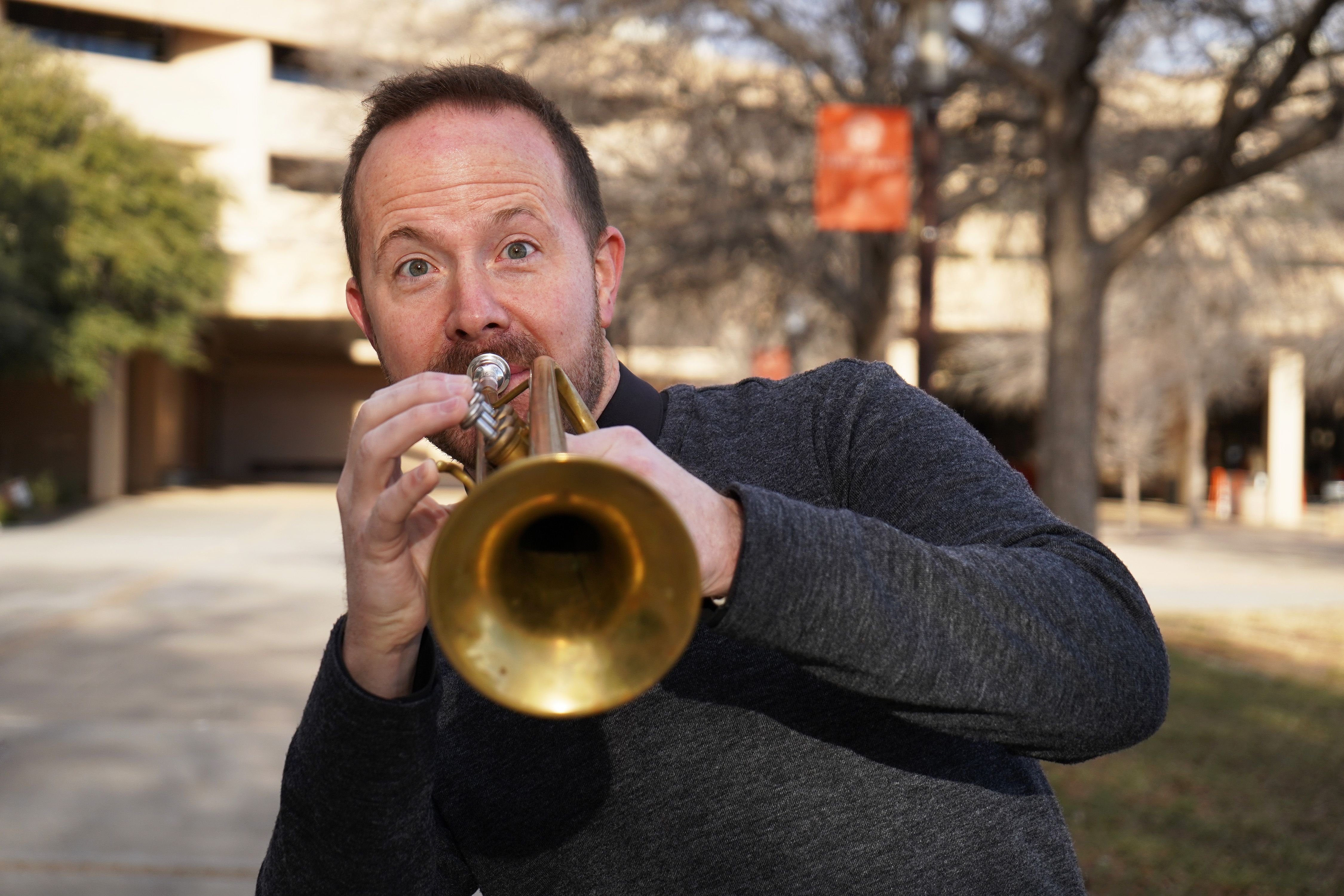 Eric Baker plays the trumpet while posing for a photo 