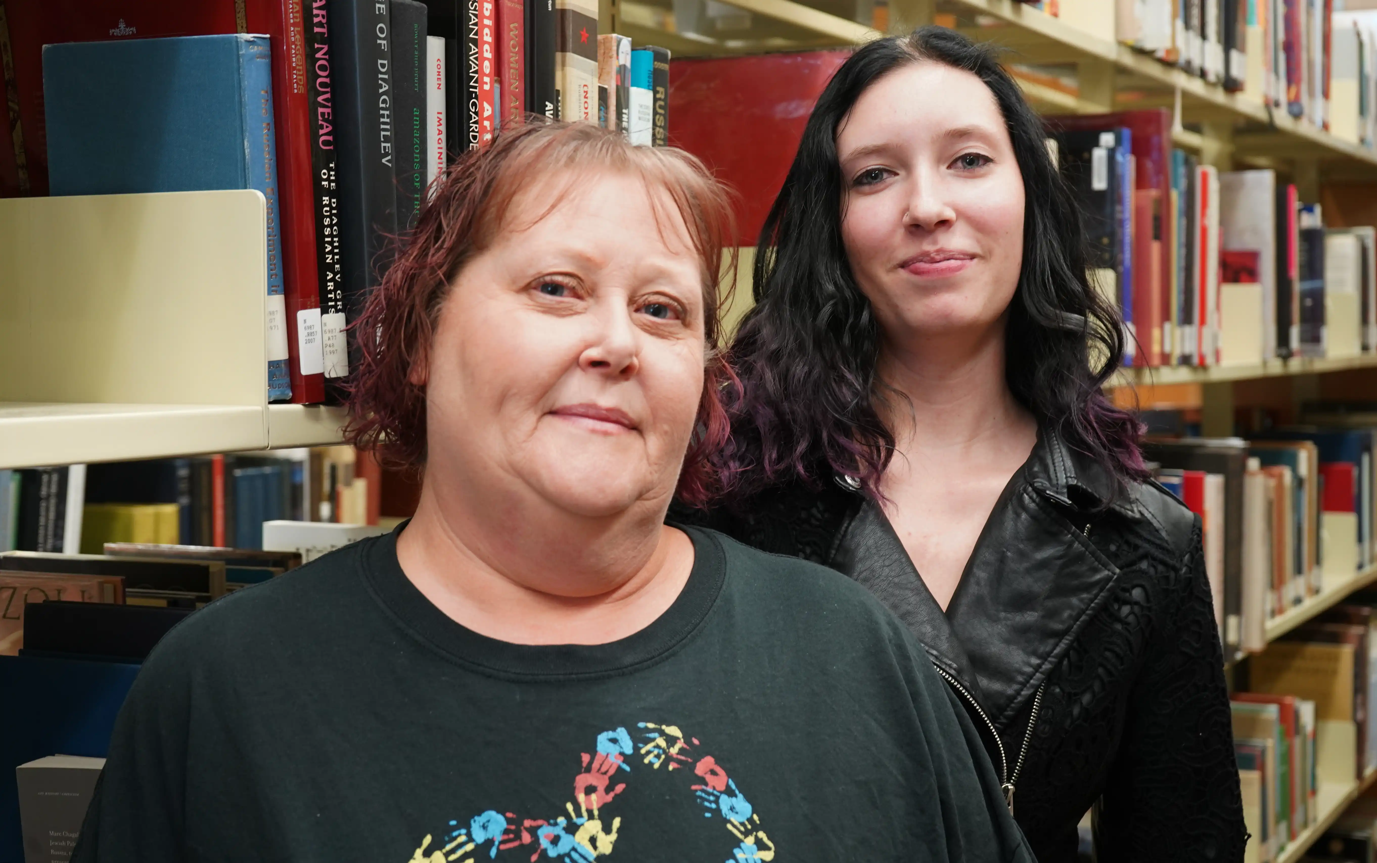 Janice and Mady Campbell standing in the on-campus library. 