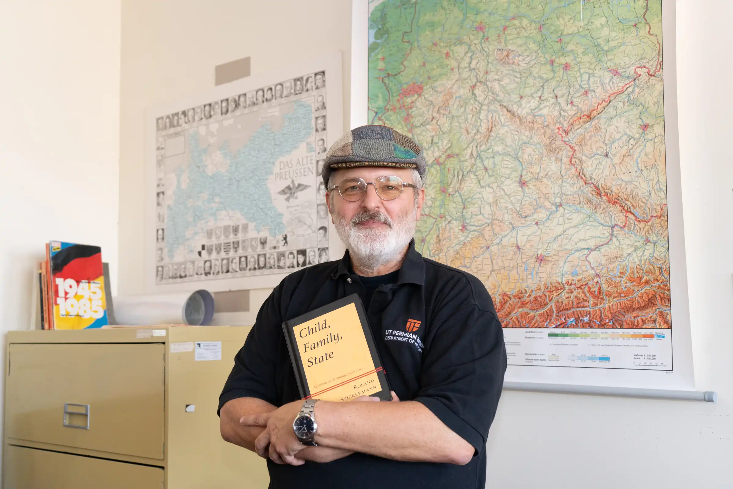 Roland Spickermann holding his book in a UTPB classroom.