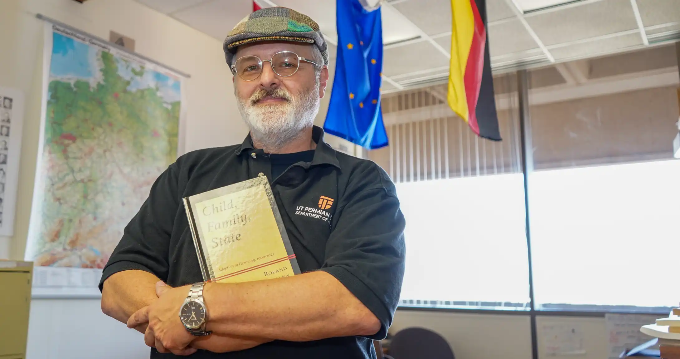 Roland Spickermann holding his first published book in a classroom at UTPB. 