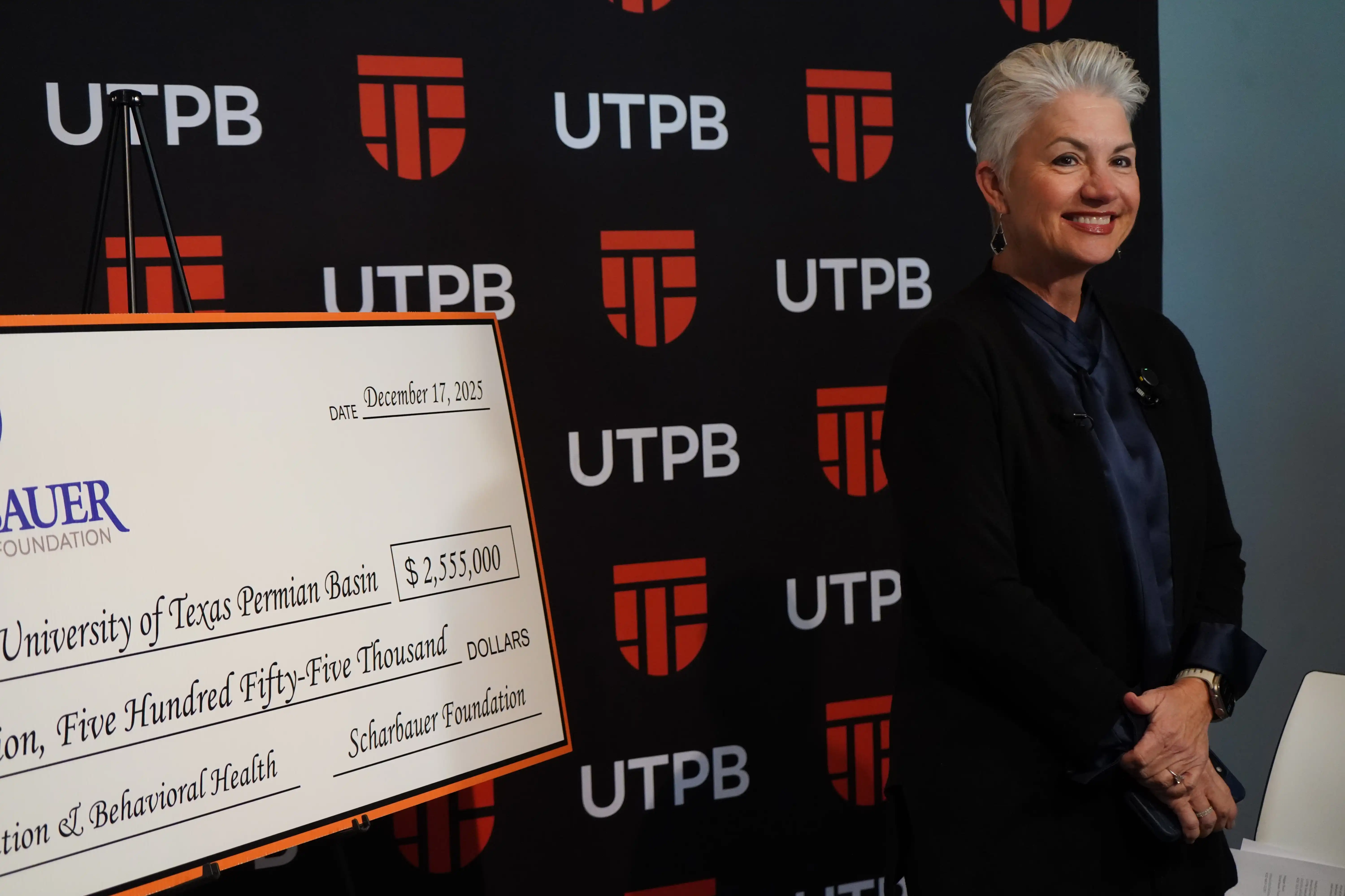 Dr. Sandra Woodley, UTPB President, standing next to the Scharbauer Foundation check. 
