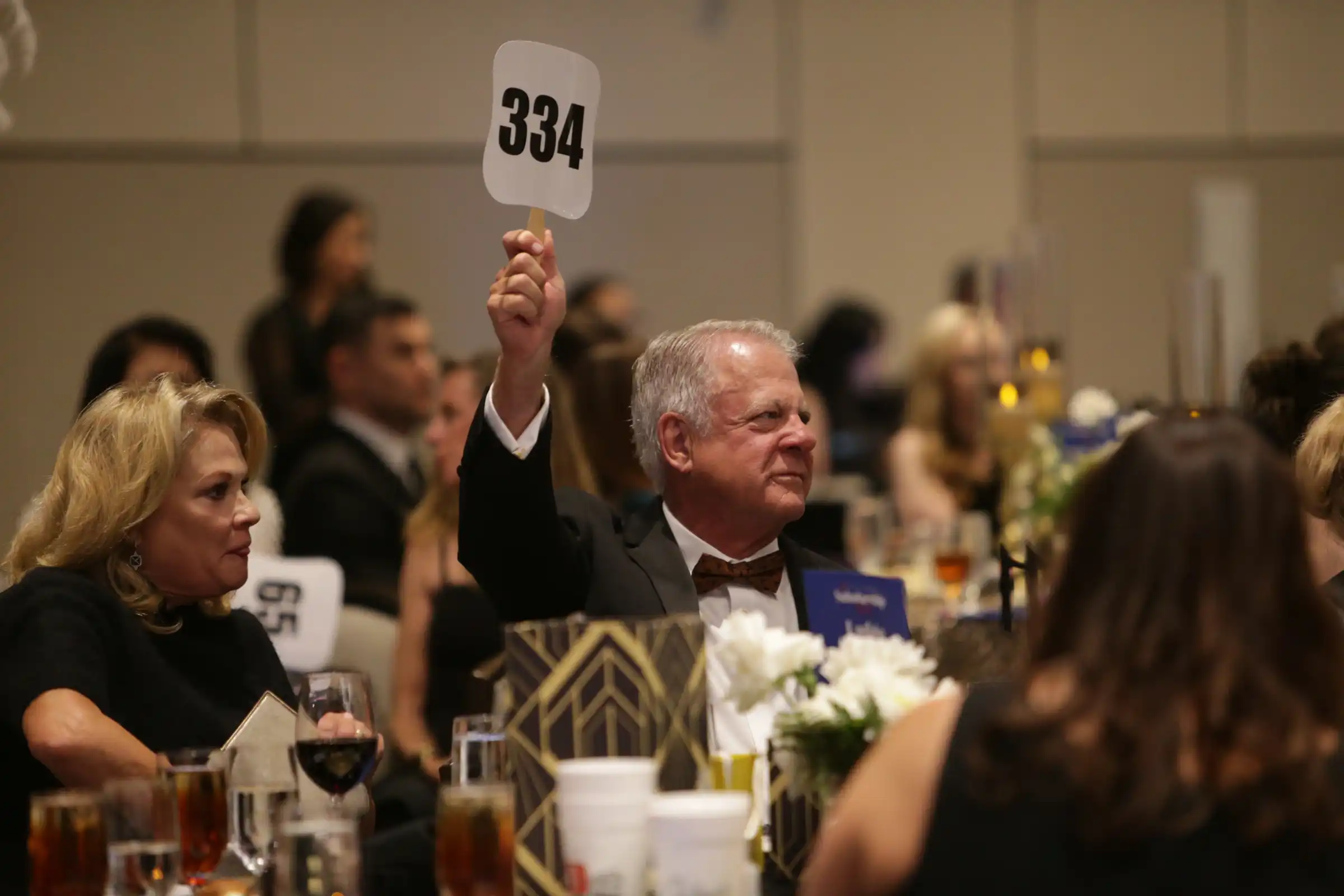Scholarship Ball attendee raising his paddle during the auction.