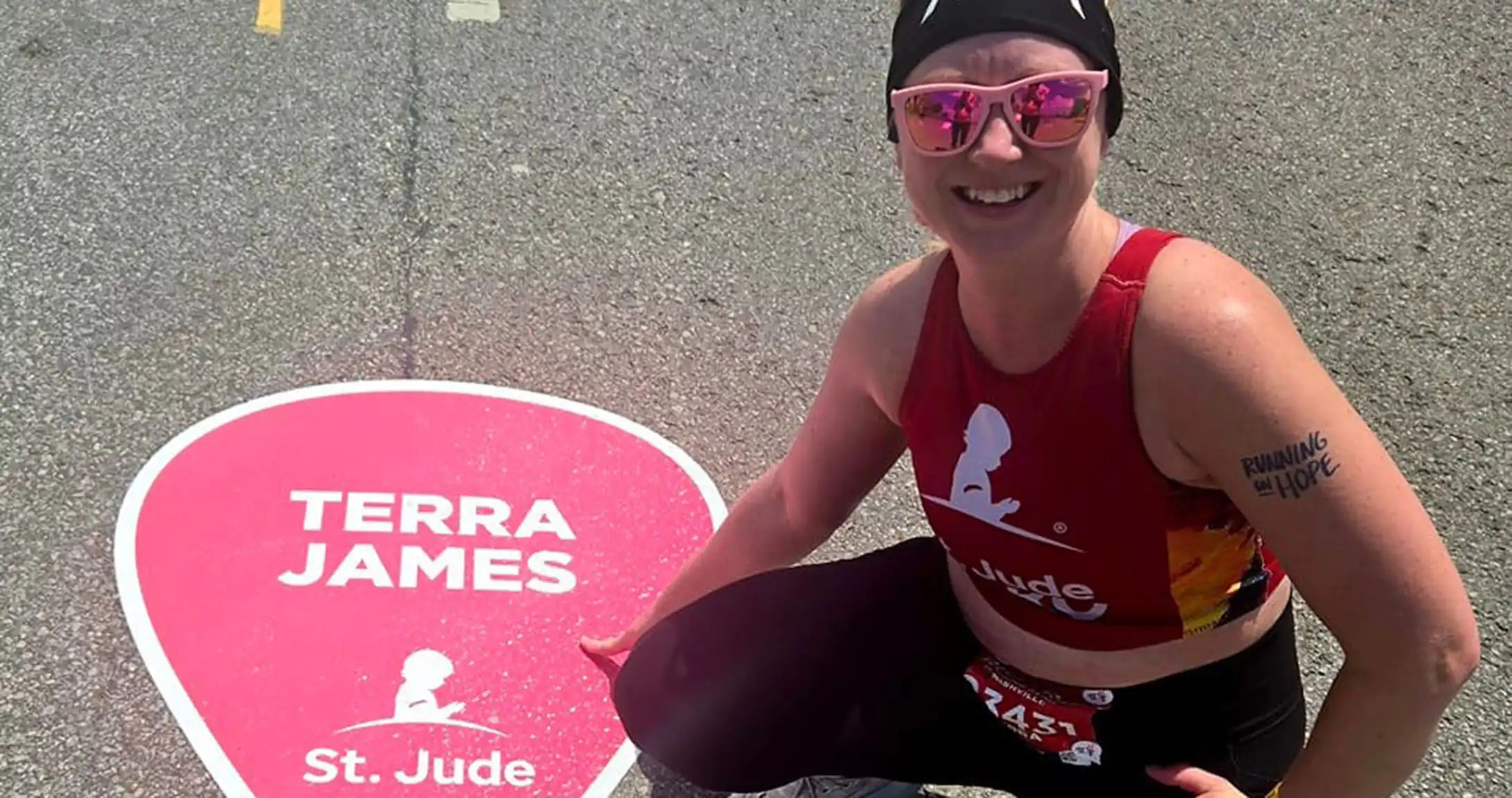 Terra James posing beside her St. Jude road sticker at the Boston Marathon