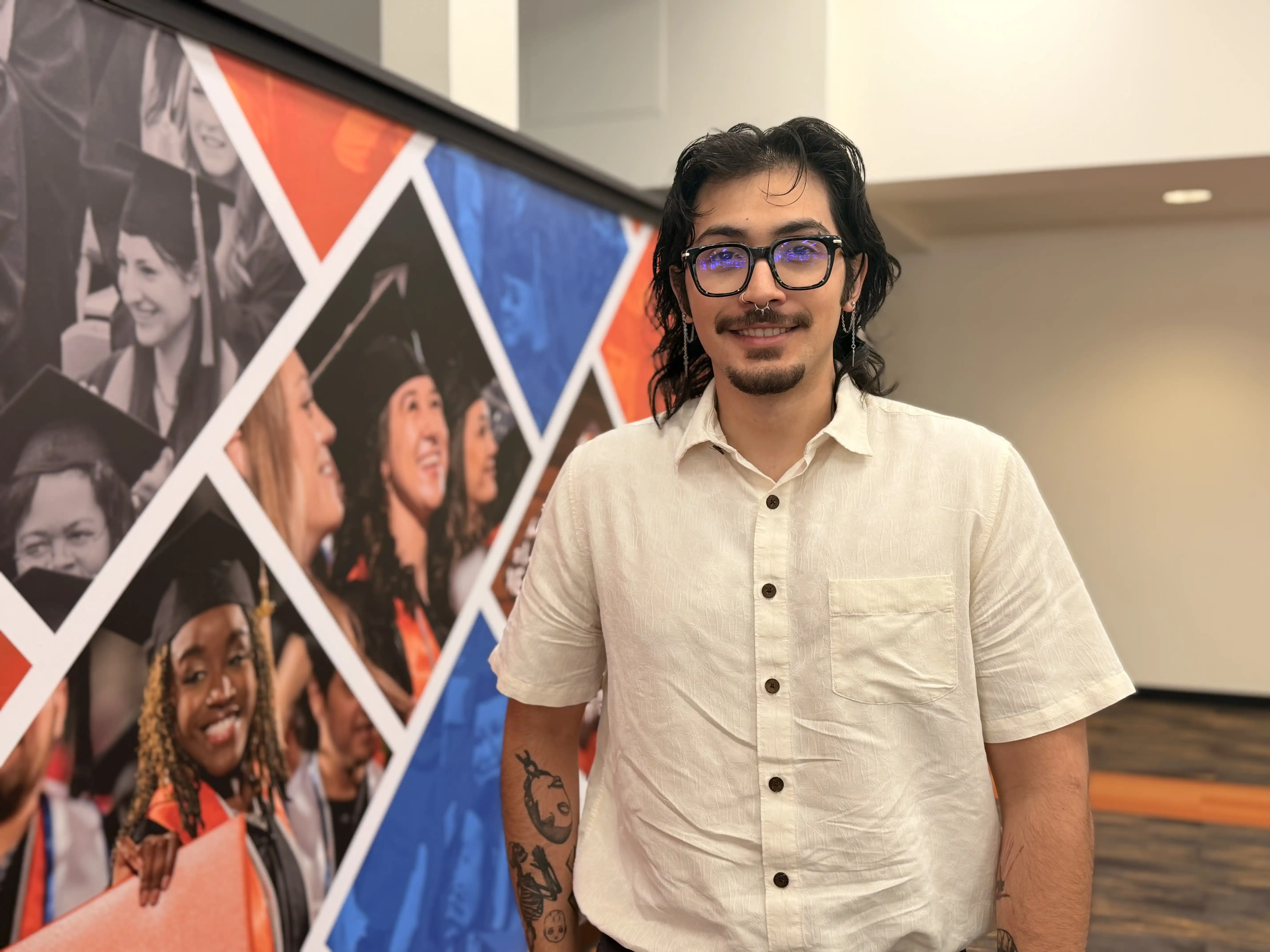 Aaron Solano smiling in front of a mural at the UTPB library. 