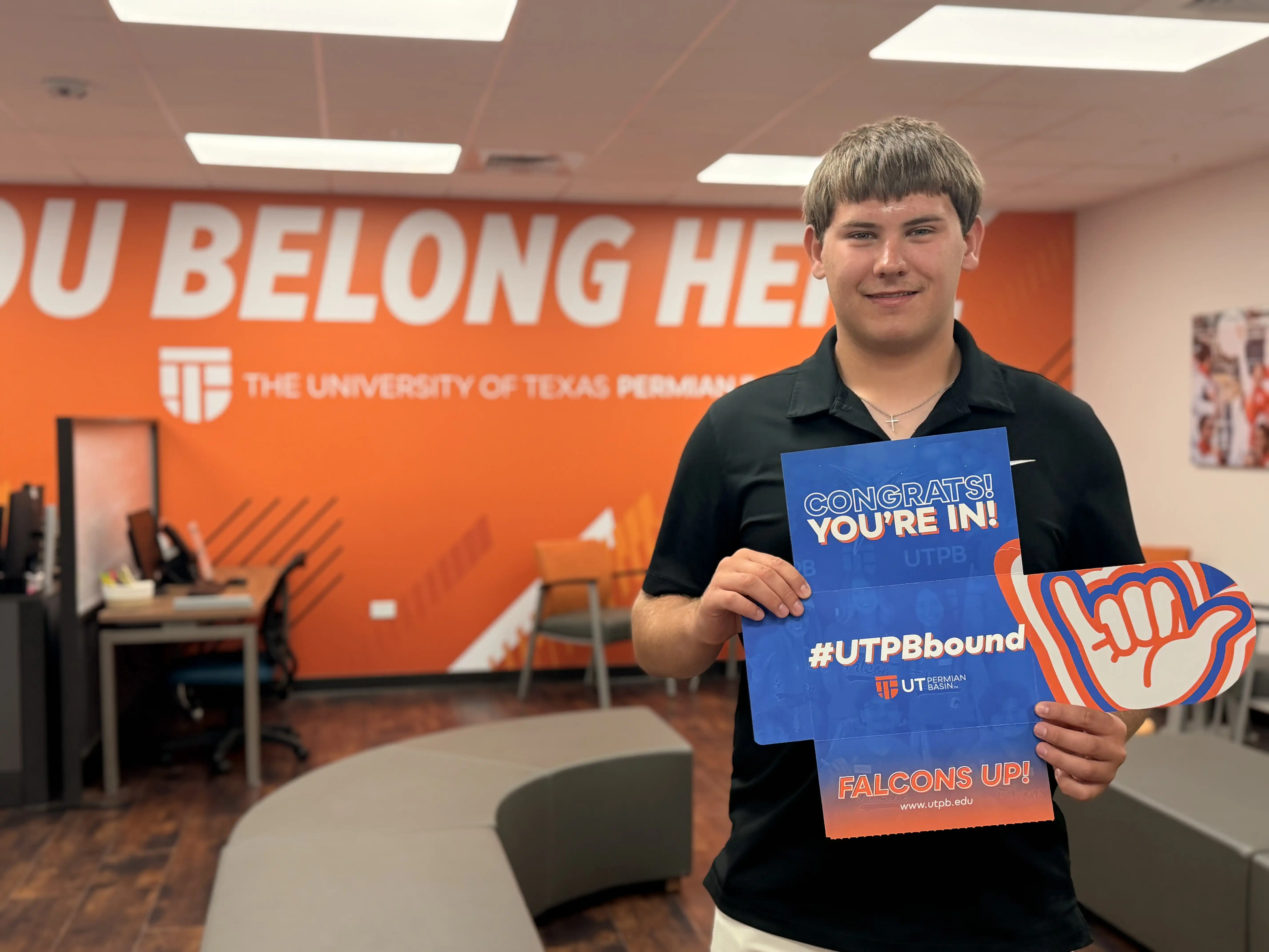 Braden Woody holding his UTPB acceptance letter in UTPB's Welcome Center.