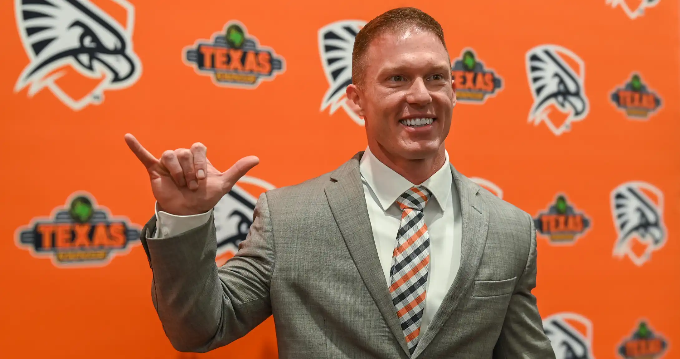 UTPB's third Head Football Coach holding his Falcons Up hand sign.