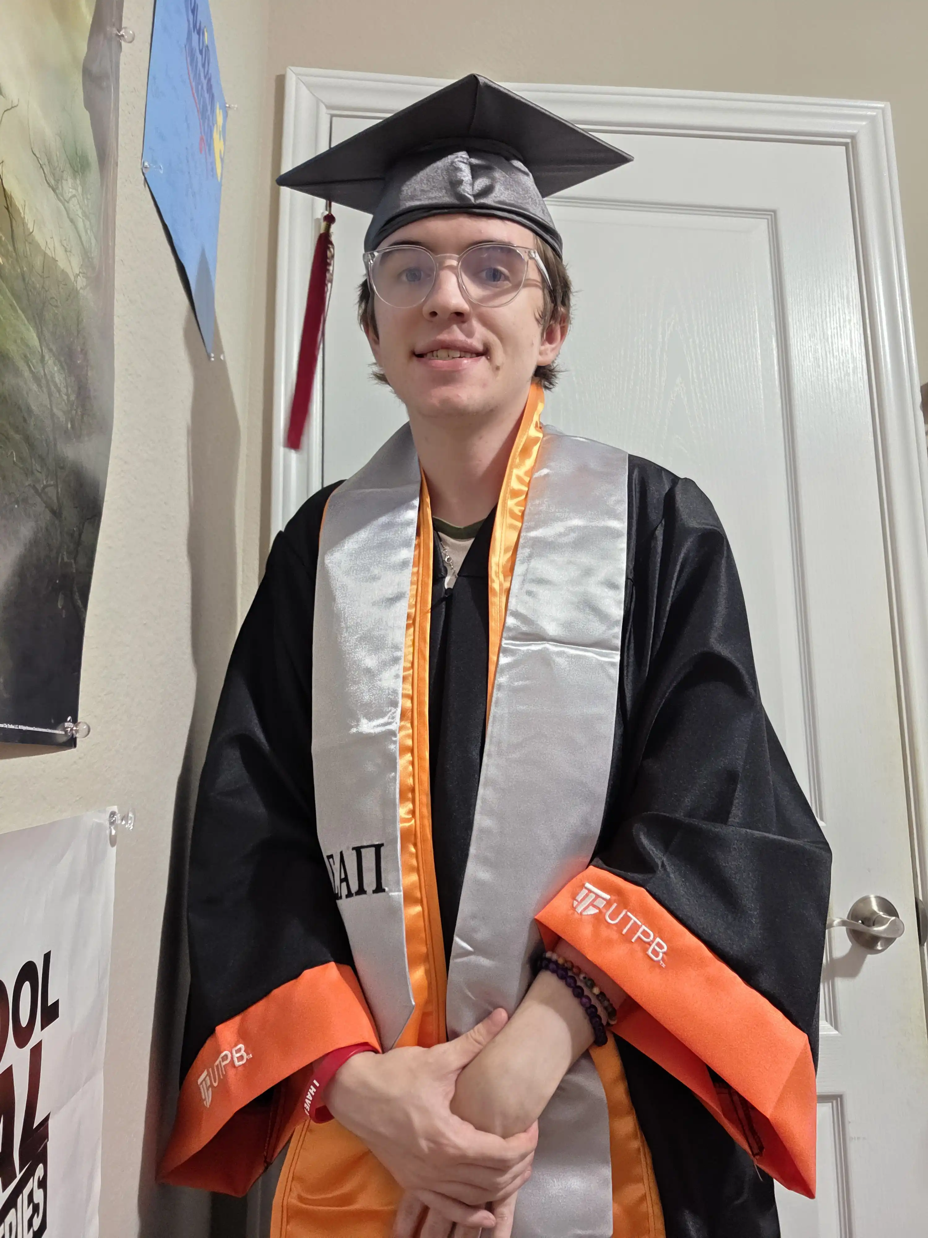 Davyn Horton standing in their UTPB graduation regalia. 