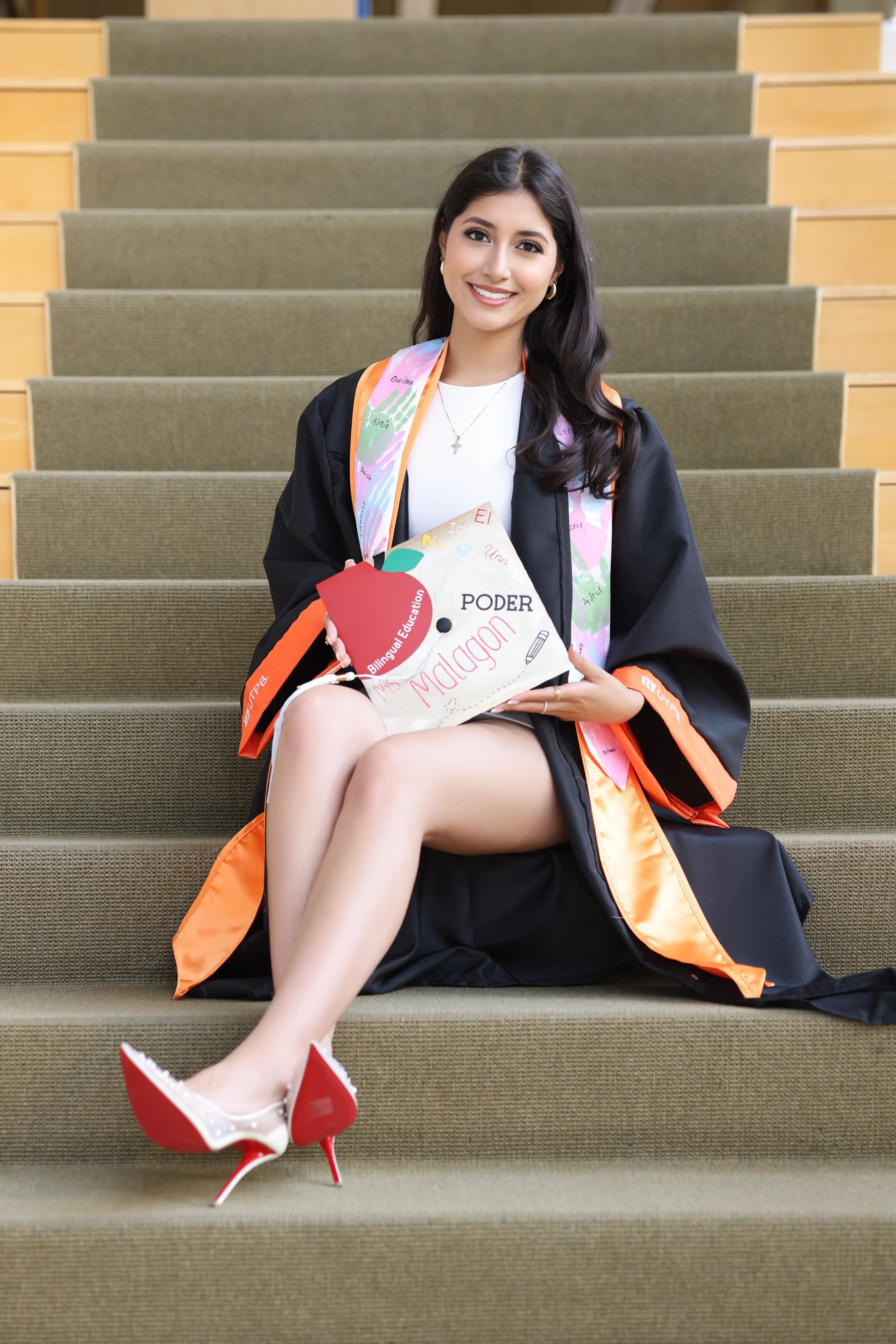 Fernanda Malagon sitting in the UTPB library while wearing her regalia.