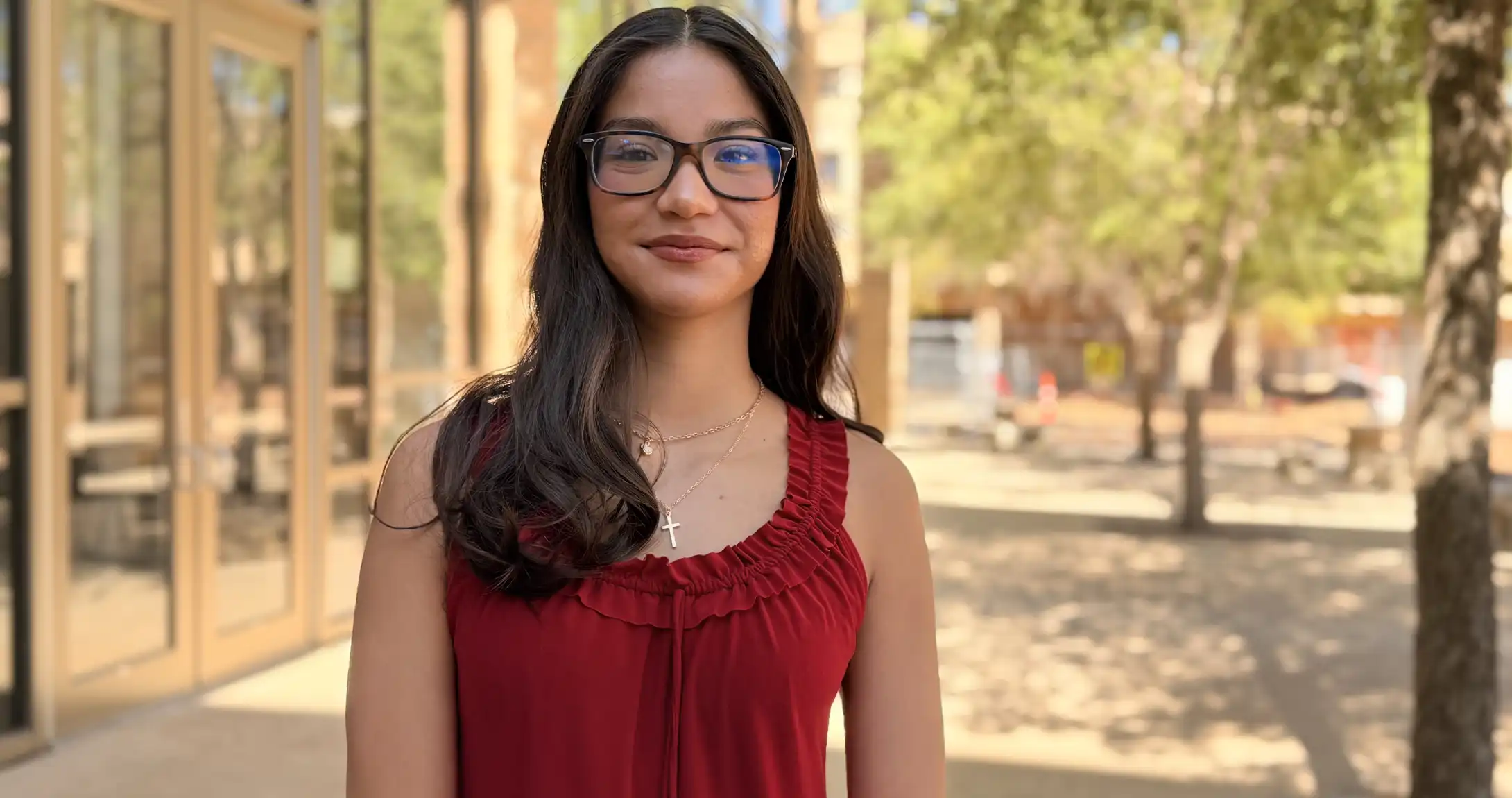 Gia Delgado standing outside of the UTPB library among trees. 