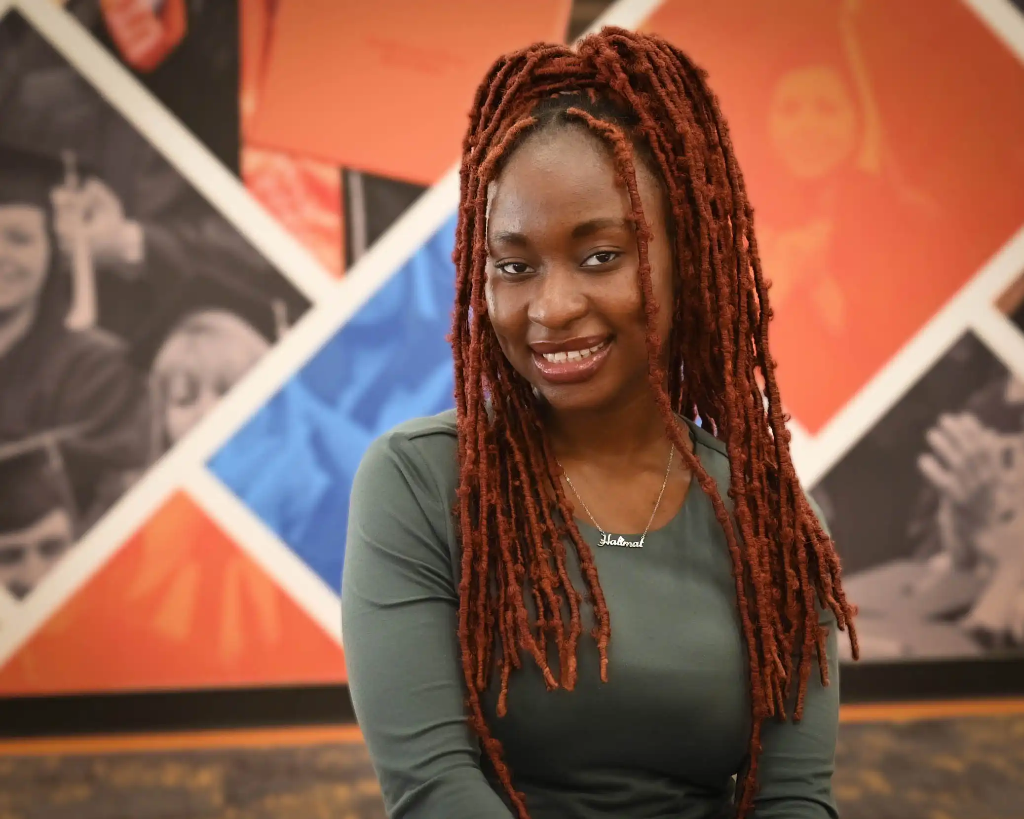 UTPB student Halimat Popoola sitting in the on-campus library in front of a mural. 
