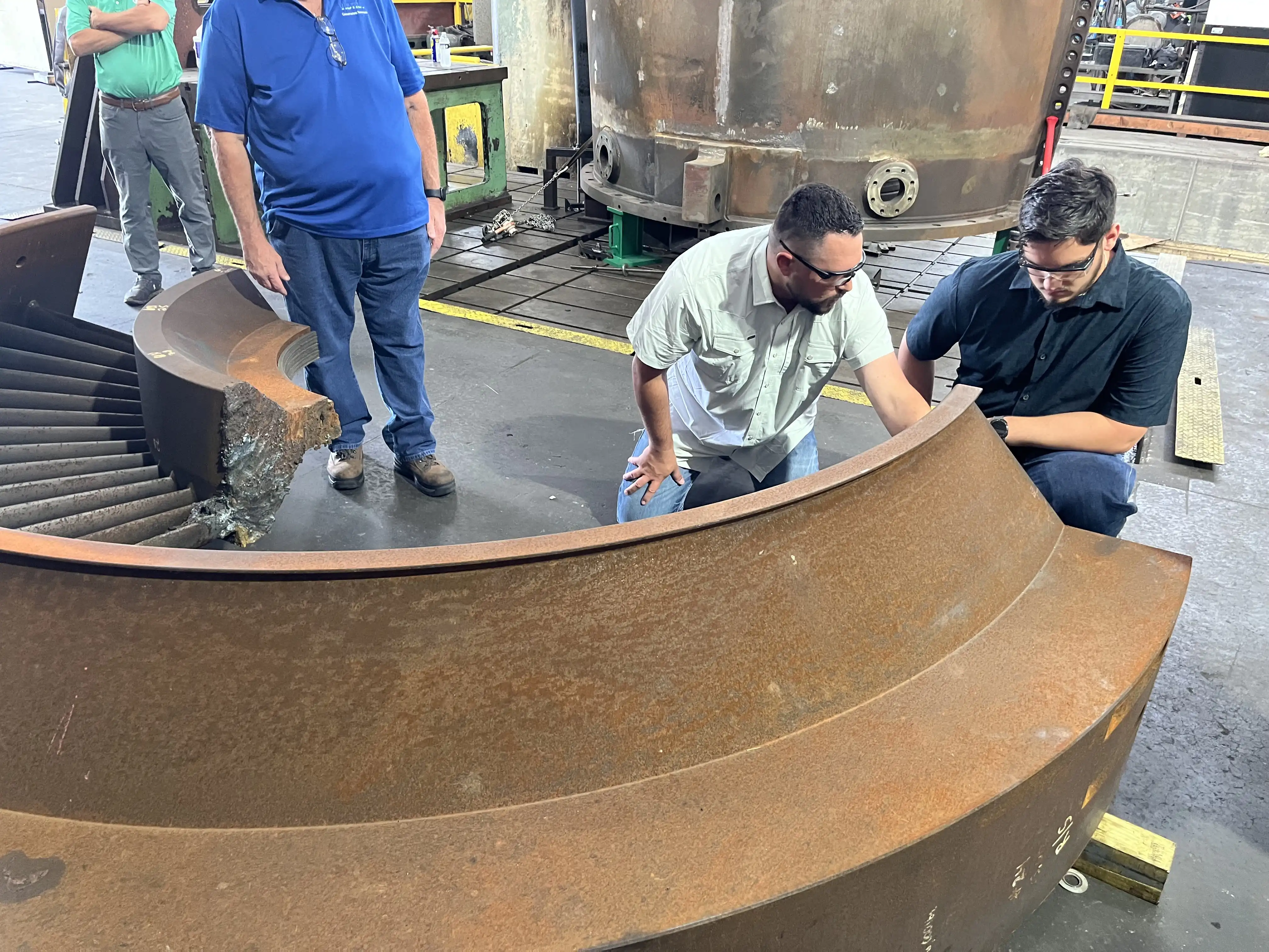 Jax in a fabrication work area looking at parts for a power plant.