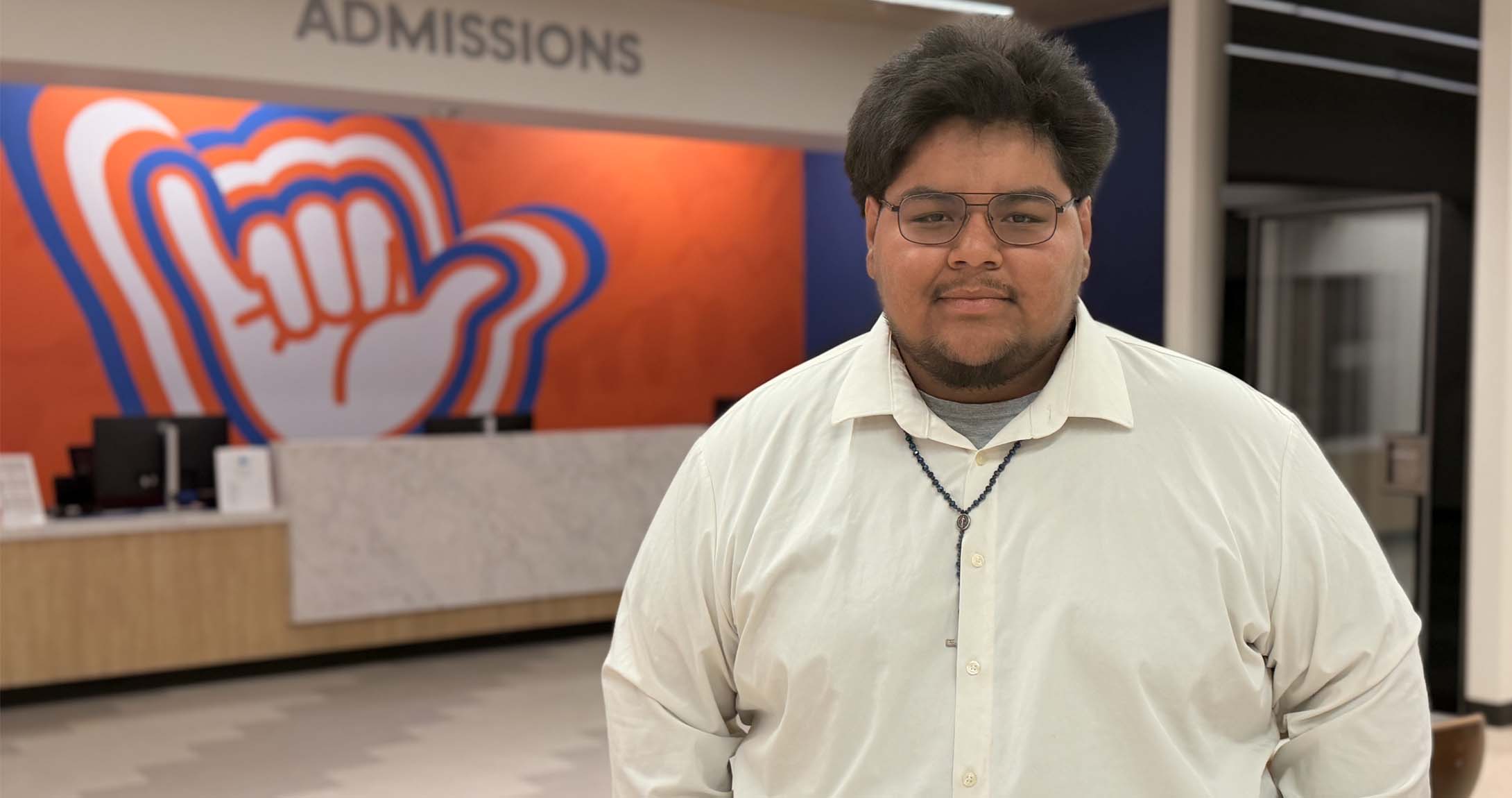 Jay Sanchez standing on campus in front of a UTPB mural. 