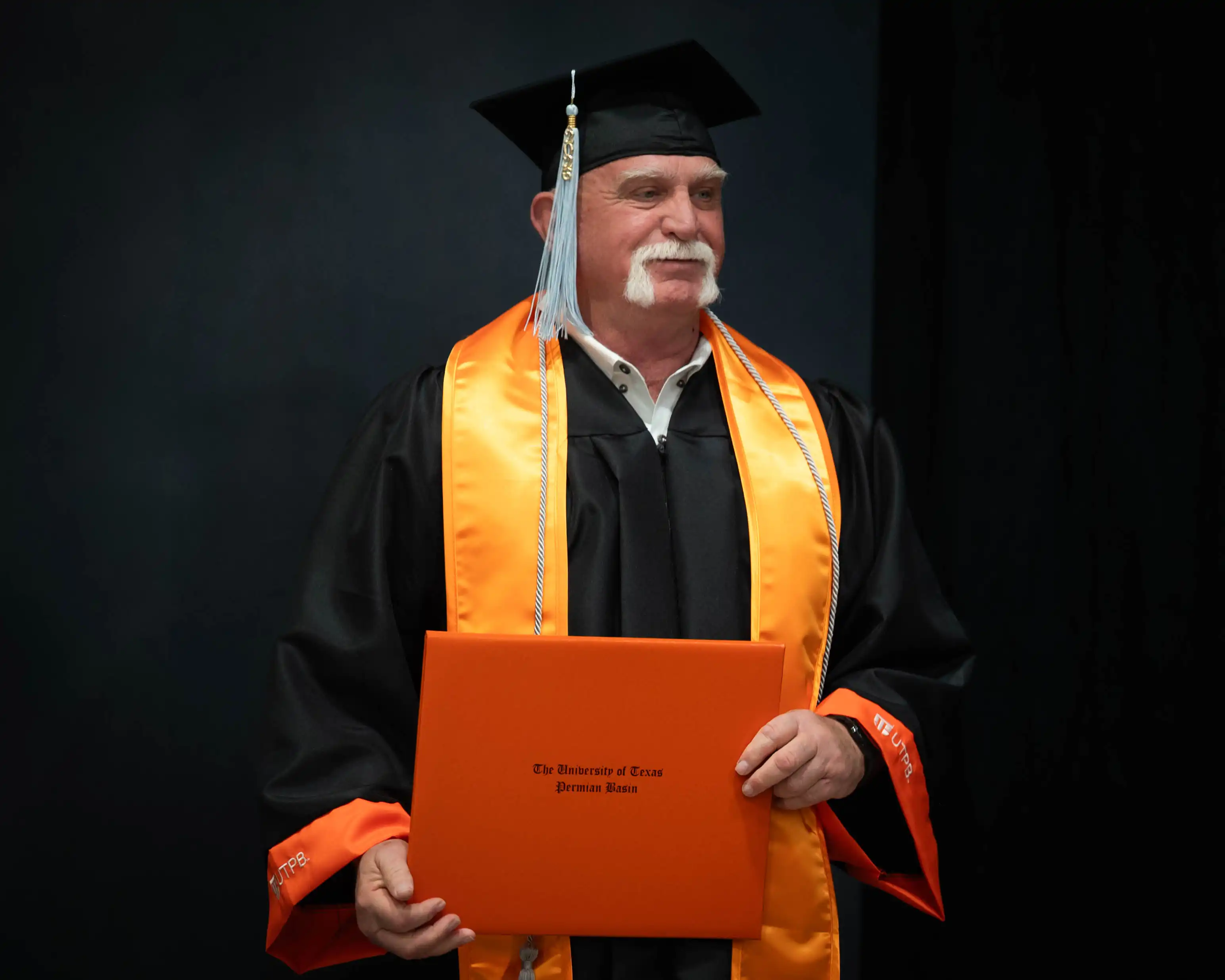 Larry Wallum holding his diploma at UTPB's Spring 2026 graduation.