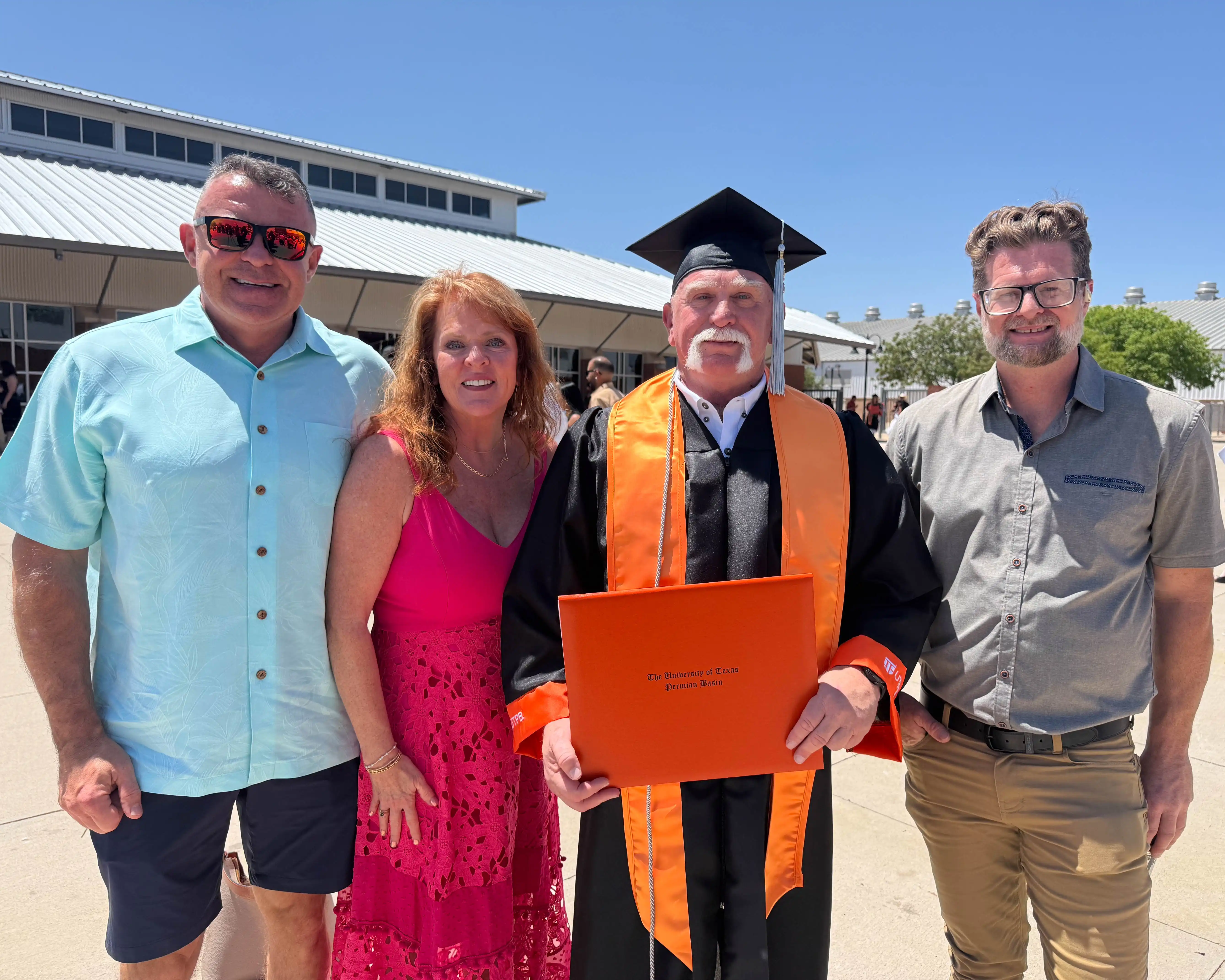 Larry Wallum standing in his regalia with his family after commencement. 
