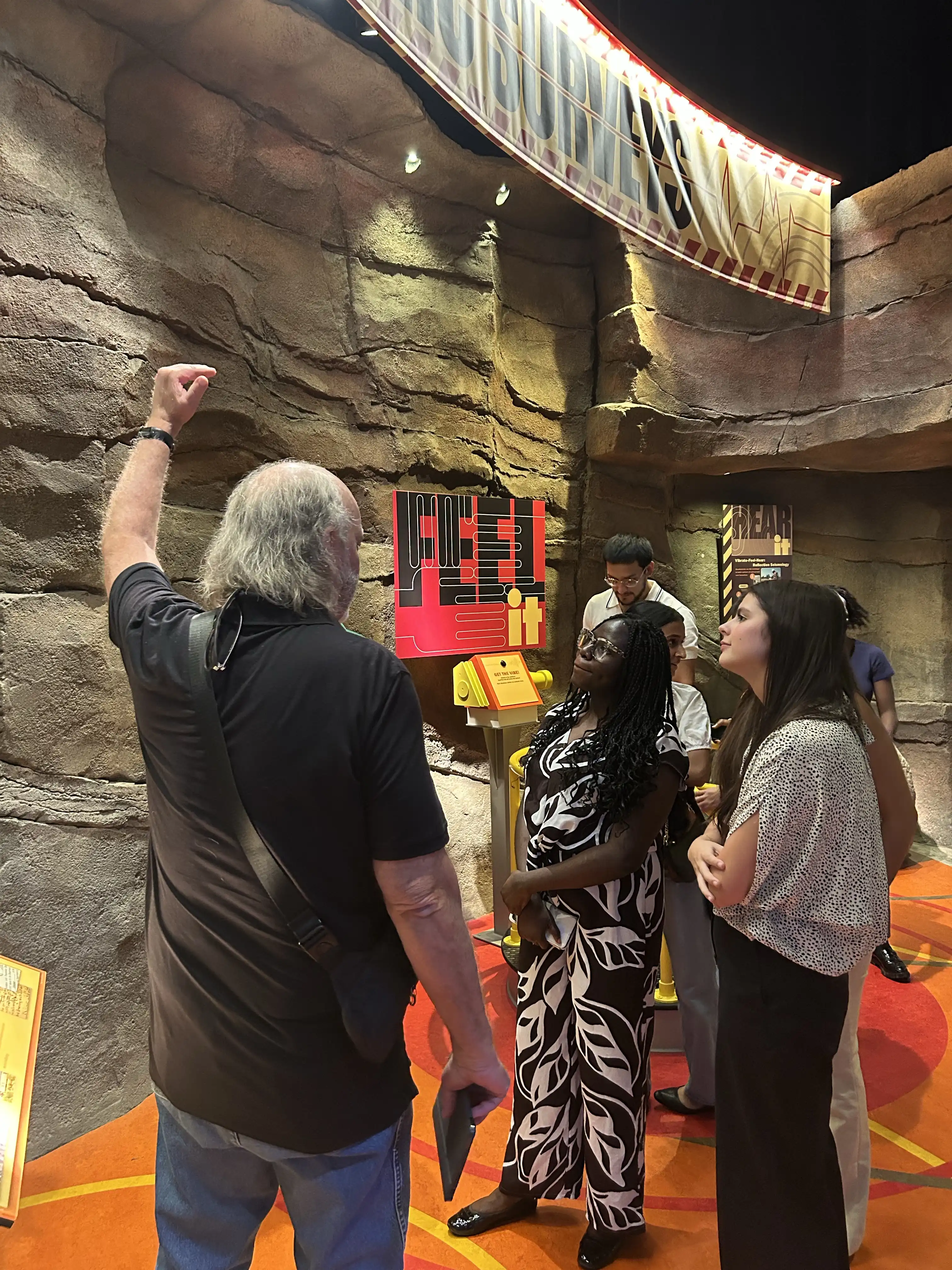 Tobechukwu Ude Akpeh with other learning from a guide next to an exhibit. 