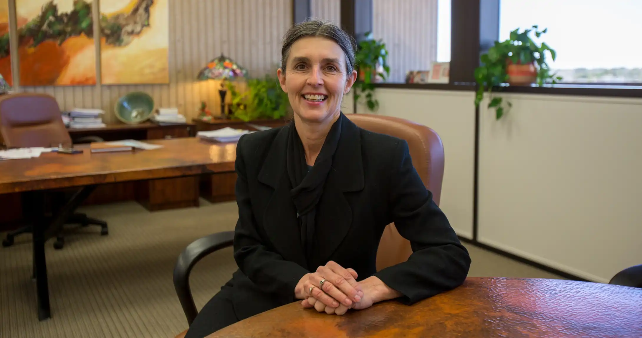Dr. Rebecca Babcock smiling and sitting in a chair in an office. 
