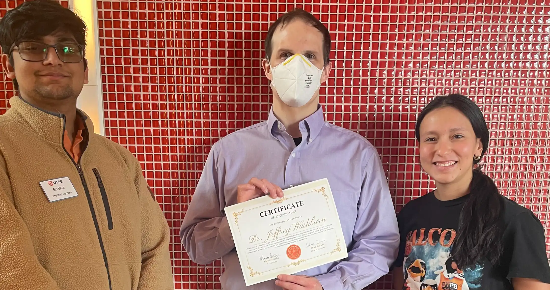 An image of the Student Government President and Vice President awarding a professor the SGA Faculty/Staff member of the week award.