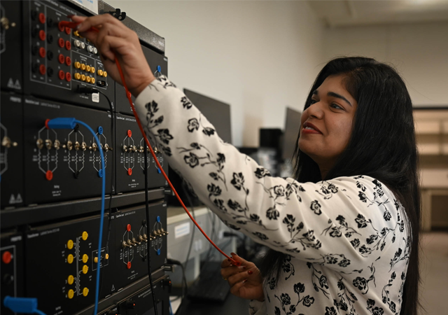 Professor Santoshi Pedapati showing members of the Society for Women Engineers student organization how to test electrical circuit response with lab based power equipment.