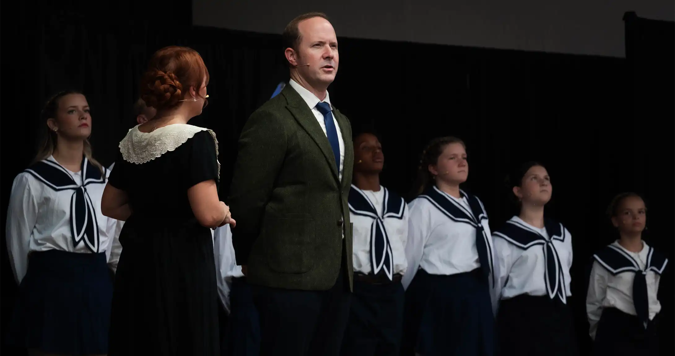 Eric Baker standing on stage with other performers for the Sound of Music.