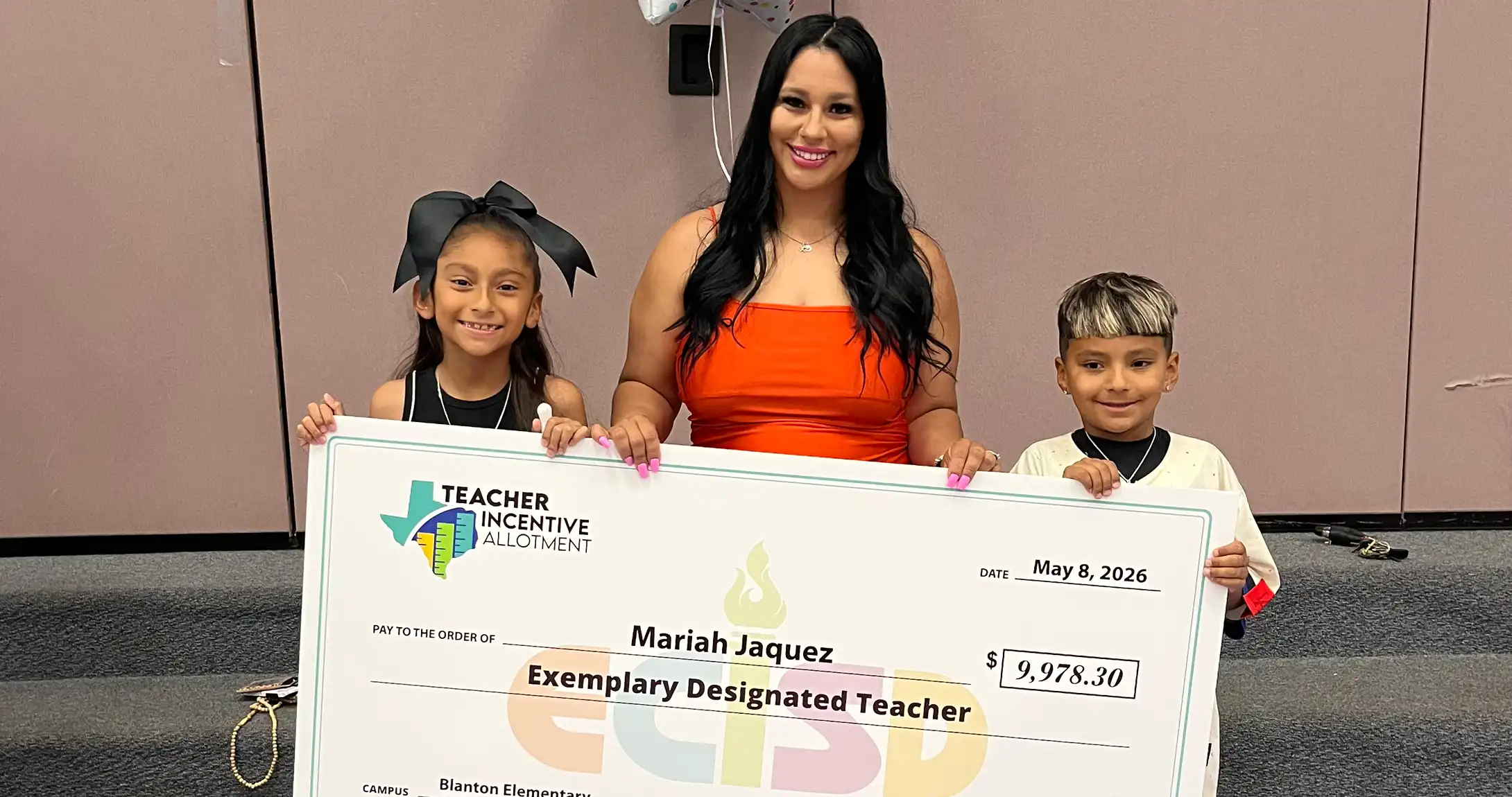 TIA award winner Mariah Ramirez posing for a photo with her kids after being awarded her ceremonial check.