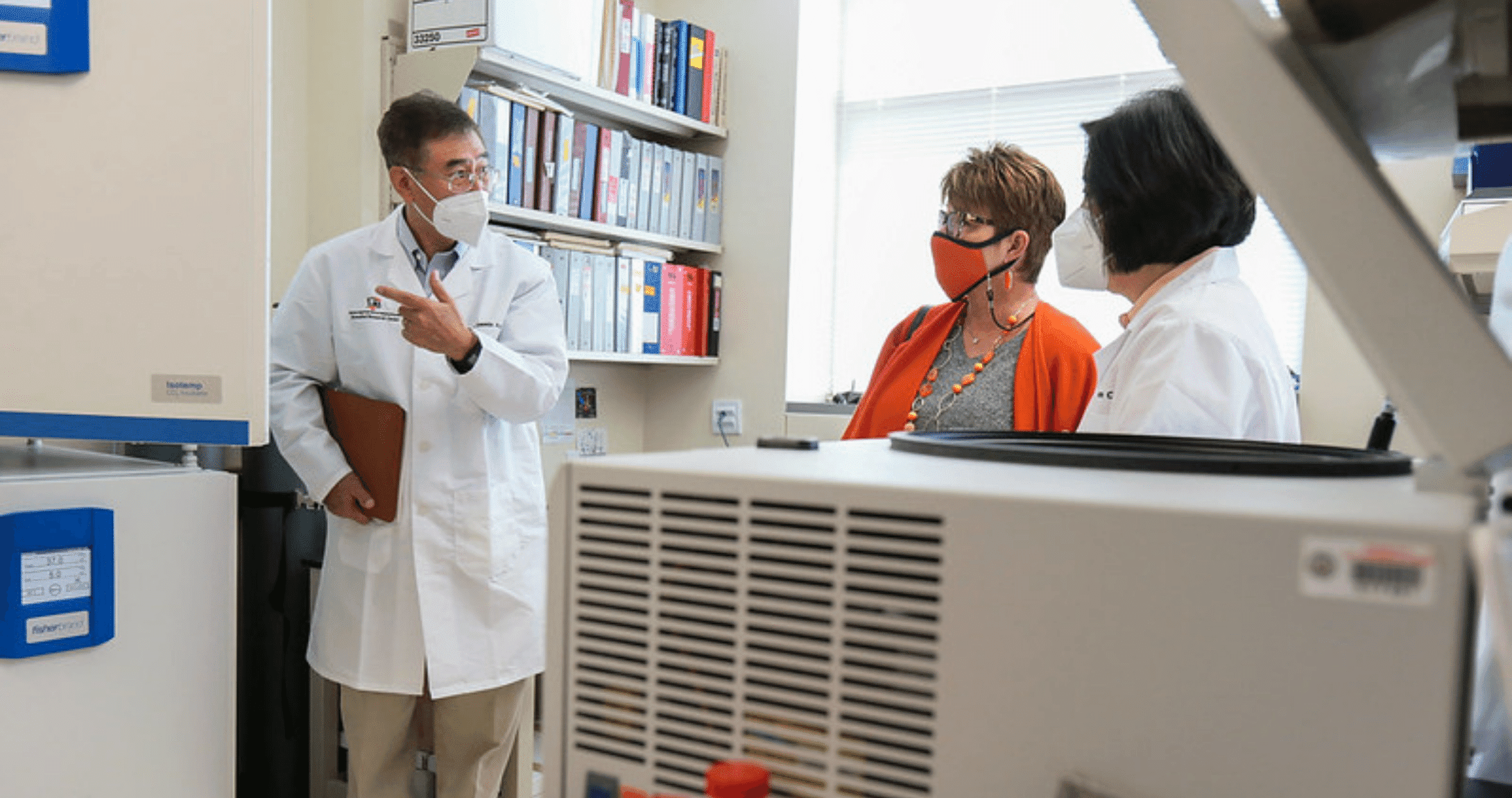 Two professors show president Woodley research lab