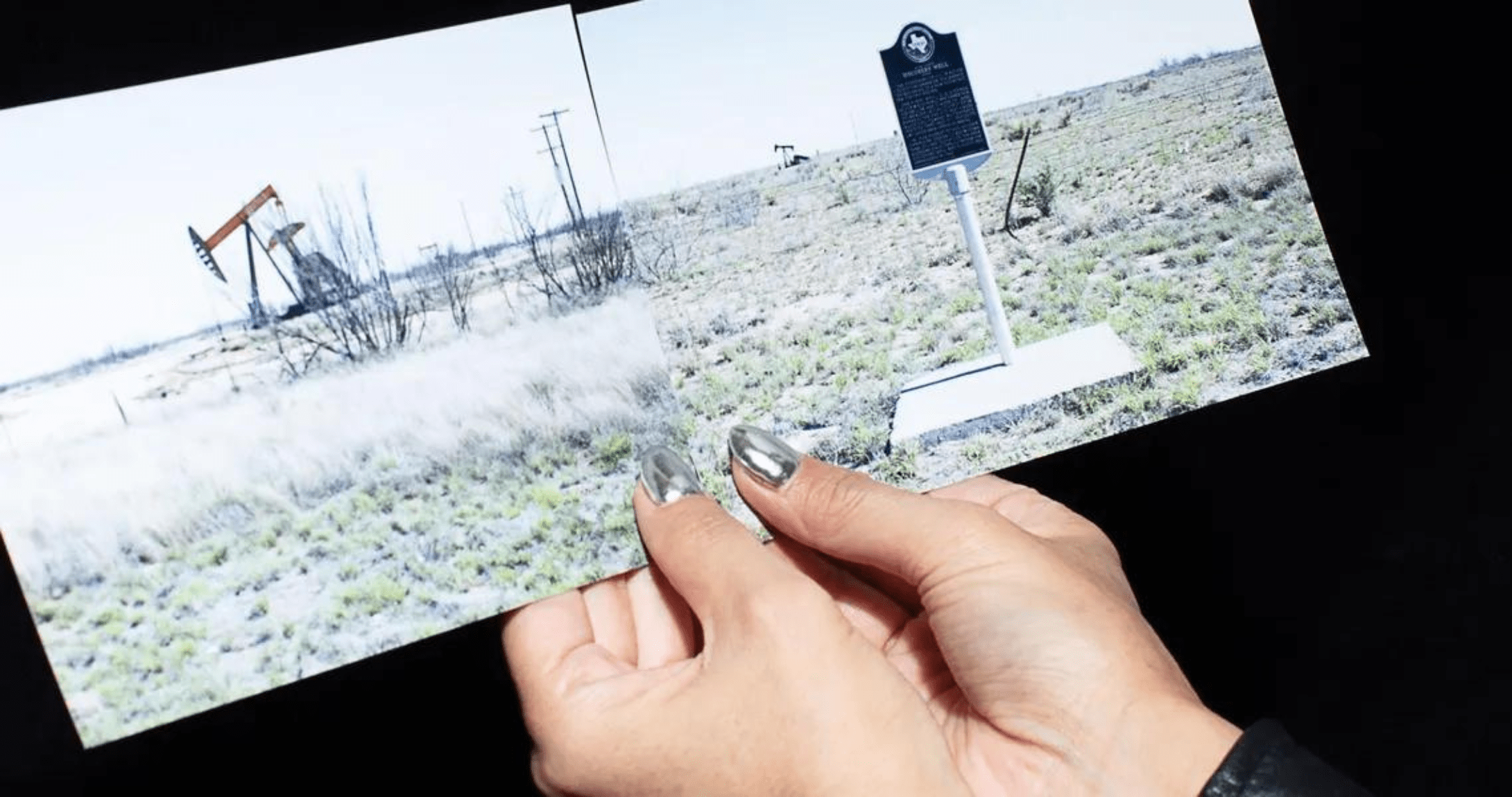 hands holding picture of texas oil rig